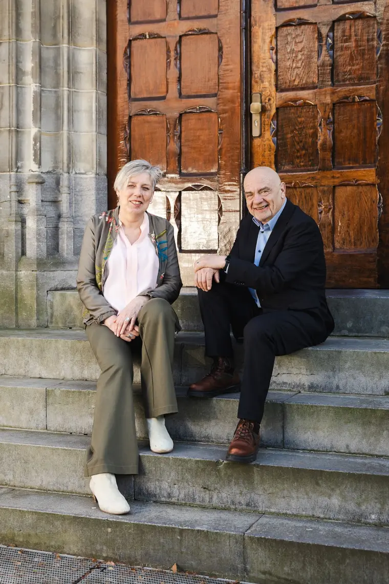Mieke Nauta en Rudi Sijbring op de trap voor een houten kerkdeur